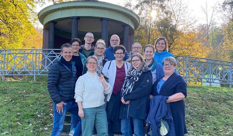 Frontalbild von Gruppe an Erwachsenen vor grünem Hintergrund.