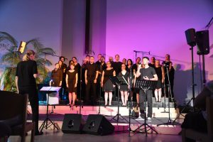 Singende Gruppe von schwarz gekleideten Menschen, einer singt ein Solo.